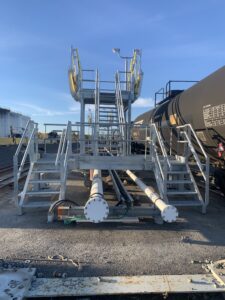 Adjustable access stairs and enclosed safety cages providing OSHA-compliant fall protection at railcar dome level.